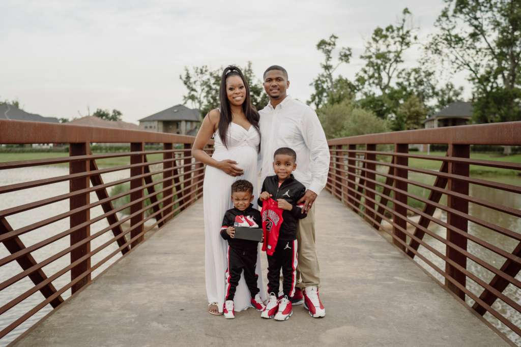 Houston family photographer capturing an outdoor family portrait of parents and children on a bridge