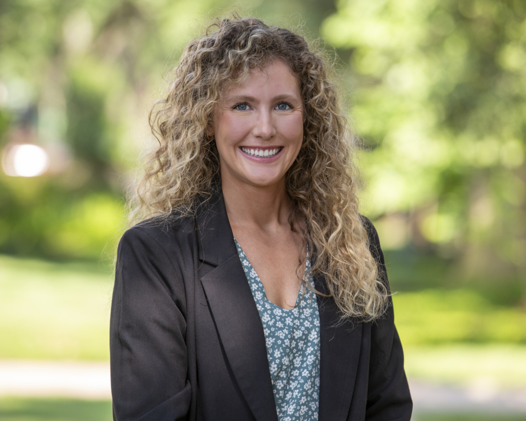 A professional corporate headshot of a businessperson in Houston, featuring a confident individual dressed in business attire, with a neutral background that highlights their professional demeanor. The lighting is even, ensuring a clear and polished image that conveys competence and approachability.