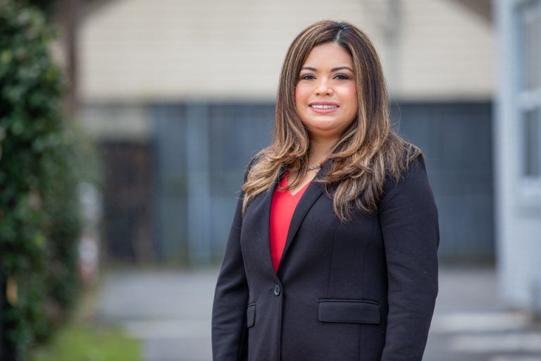 Businesswoman in a blazer smiling outdoors for professional headshot.