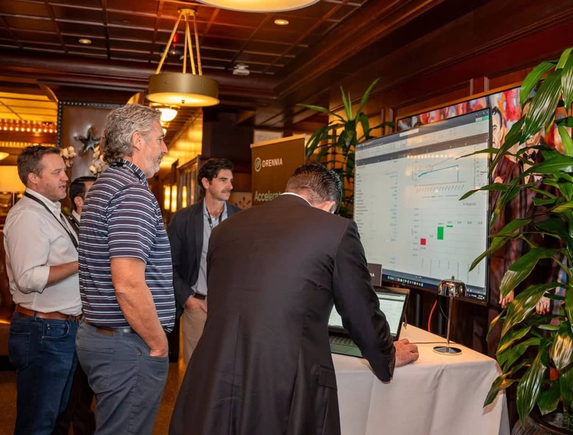 Business professionals at a corporate event analyzing data on a large screen.