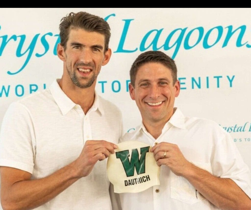 Two men smiling and holding a Dautrich banner at an event.