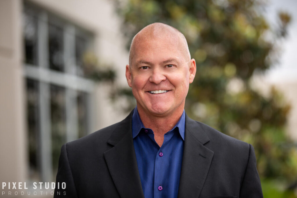 Executive headshot in Houston of an energy company leader in a navy suit, arms crossed, on a white studio background