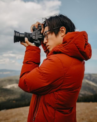 Johnny, Pixel Studio Productions videographer, shooting with a camera outdoors in a red jacket