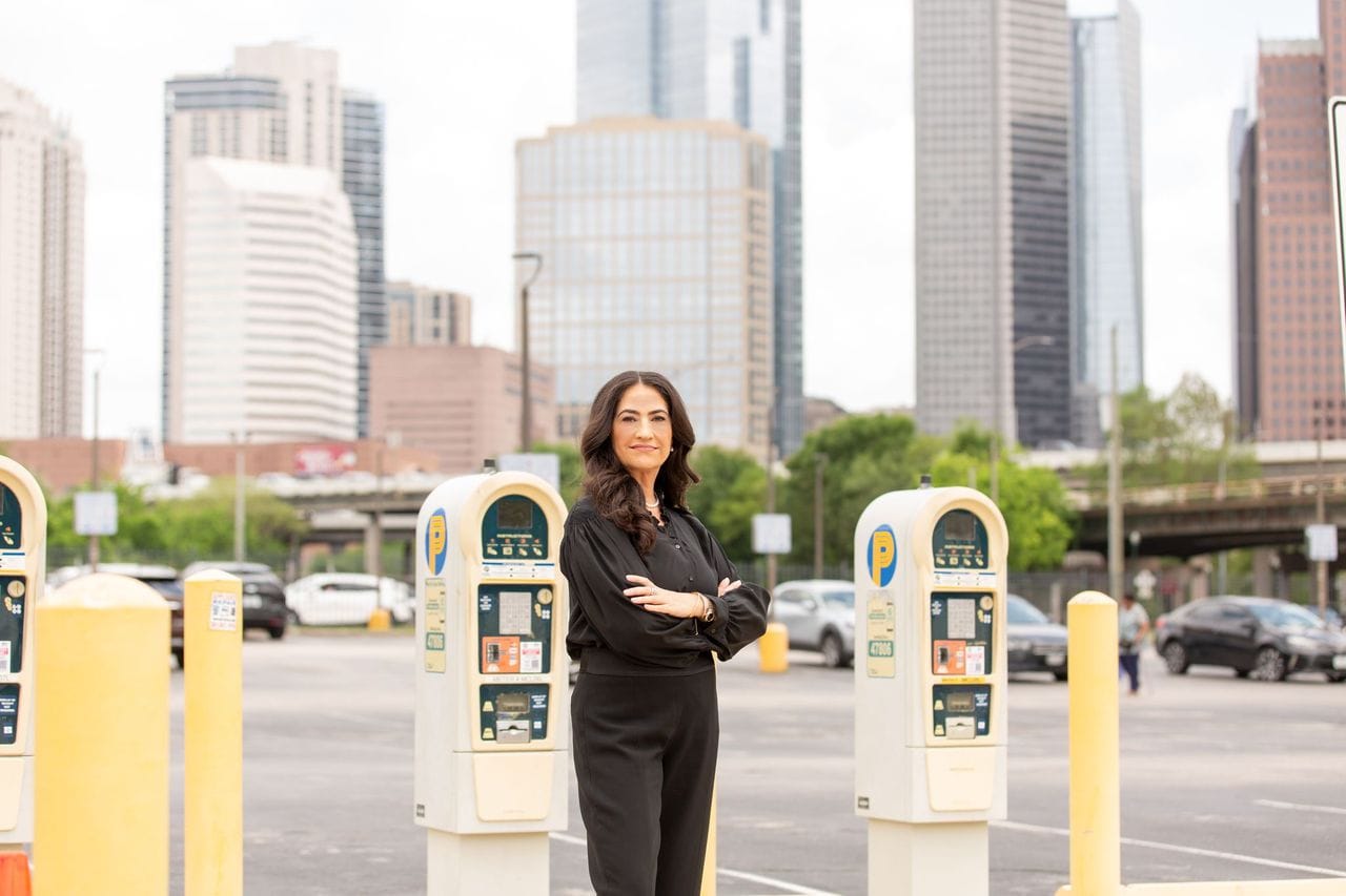 Woman standing in parking lot with city skyscrapers in background.