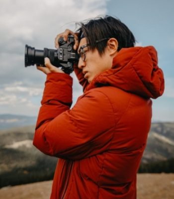 Johnny, Pixel Studio Productions videographer, shooting with a camera outdoors in a red jacket